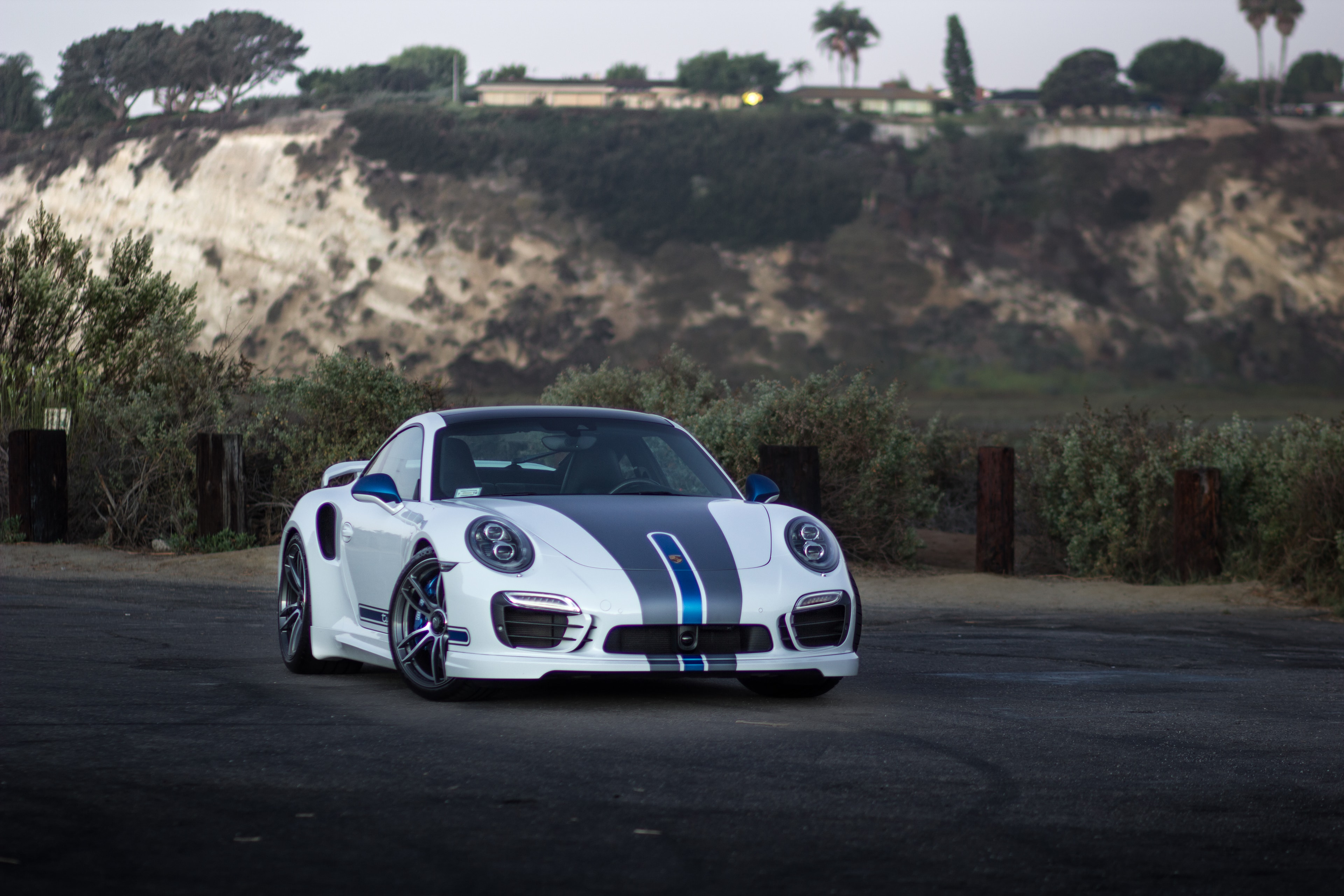 TECHART 911 Turbo S — white with blue racing stripes and full TECHART aero package. Shot at the cliffs at dusk.